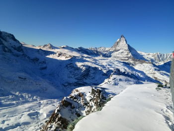 Scenic view of snowcapped mountains against clear blue sky