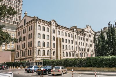 Cars on street by buildings against clear sky