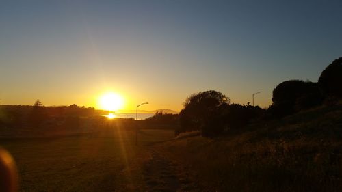 Silhouette field against clear sky during sunset