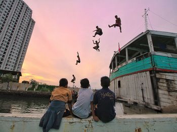 People flying over city against sky during sunset