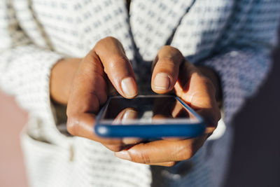 Hands of woman using smartphone, close up