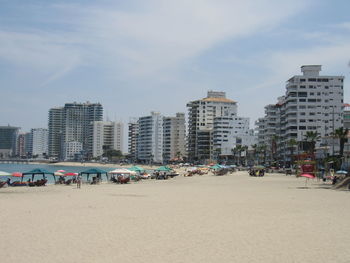 Group of people on beach against buildings in city