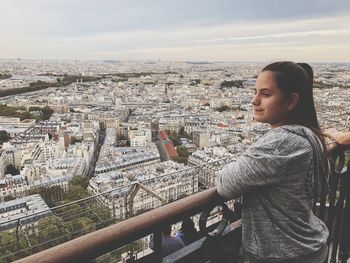 Woman looking at cityscape against sky