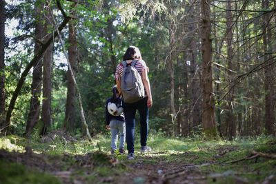 Full length of woman and girl walking in forest