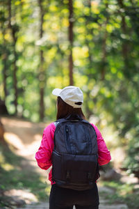 Rear view of woman standing against trees in forest