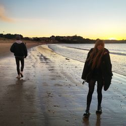 Rear view of women walking on beach
