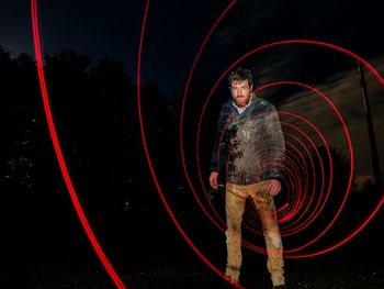 Portrait of man with red light trail in dark at night