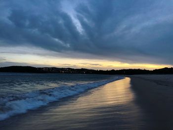 Scenic view of beach against sky at sunset