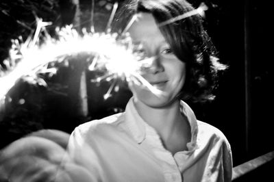 Portrait of smiling woman holding lit sparkler