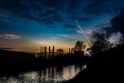 Silhouette bridge over river against sky during sunset