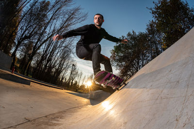 Low angle view of man jumping against trees