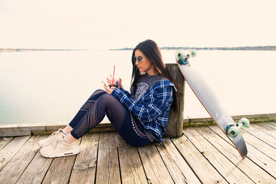 Woman sitting on wood against sky