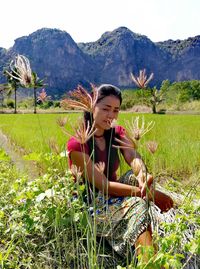 Young woman smiling while standing on field against mountains