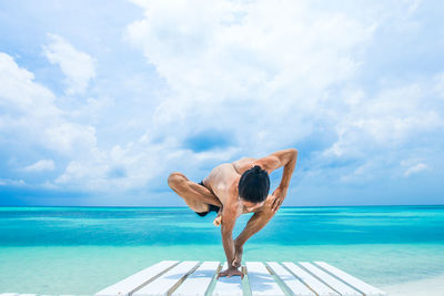 Woman relaxing by swimming pool against sky