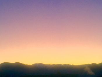 Scenic view of silhouette mountains against clear sky during sunset