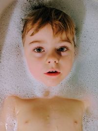 Portrait of cute boy lying in bathtub