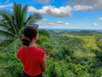 Rear view of woman standing on mountain against sky