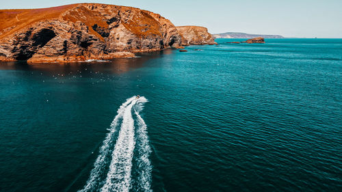 The jet ski runs in the direction of the rock on turquoise water. aerial view