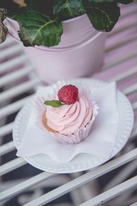 Fruity cupcake with whipped cream and raspberry on a plate