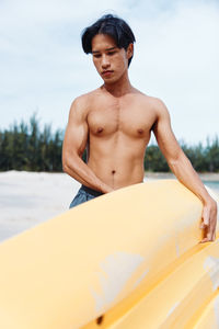 Portrait of shirtless man exercising on beach