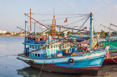 Colorful fishing boats are securely tied down directly at the pier with seaman's ropes and knots