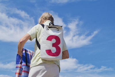 Low section of man standing against blue sky