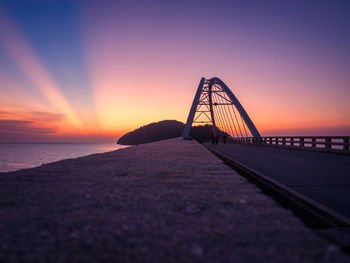 Bridge over sea against sky during sunset