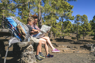 Smiling woman with son reading map while sitting on picnic table