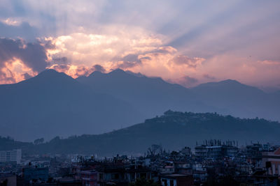 Townscape by mountains against sky at sunset