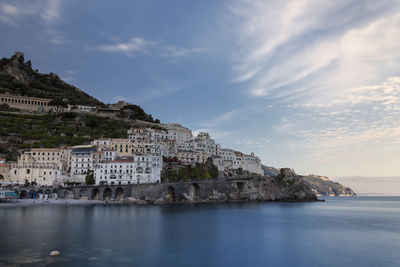 Buildings by sea against sky in city