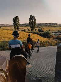 Rear view of people riding horses