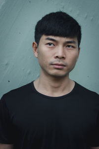 Portrait of young man standing against wall