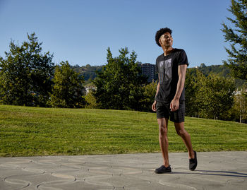 Full length of young man standing by tree against sky