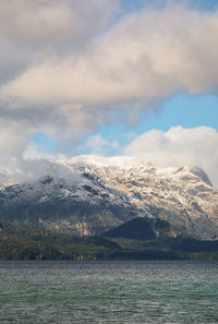 Scenic view of sea by snowcapped mountain against sky