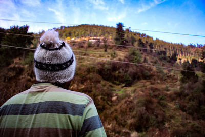 Rear view of man on mountain against sky