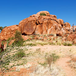 Rock formations on landscape against clear blue sky