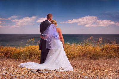Rear view of wedding couple on landscape against sea