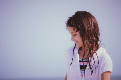 Smiling girl with wet hair against sky