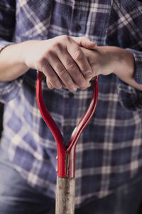 Midsection of farmer holding pitchfork's handle