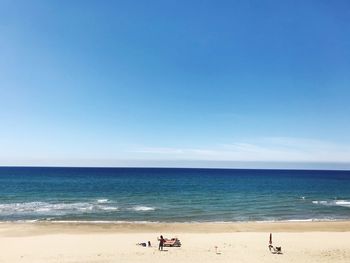 Scenic view of beach against clear blue sky