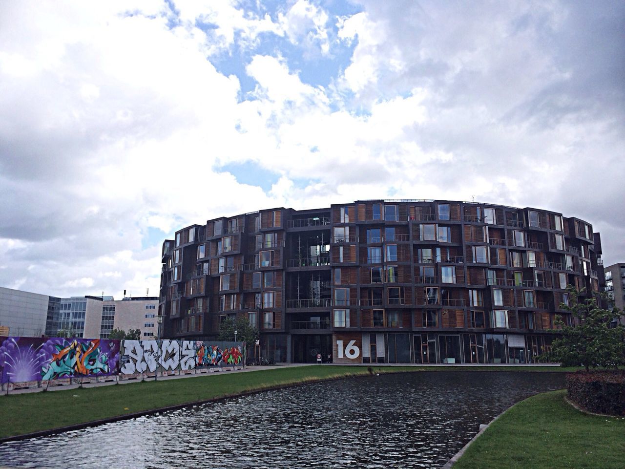 architecture, building exterior, built structure, sky, cloud - sky, city, cloudy, cloud, water, building, grass, day, outdoors, residential building, residential structure, street, tree, no people, waterfront, road