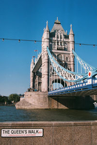 Tower bridge over thames river against clear blue sky during sunny day