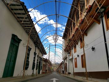 Empty road amidst buildings against sky
