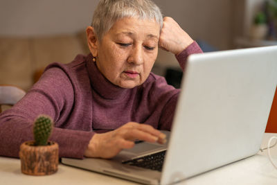 A woman sitting in front of a laptop communicates online through social networks.