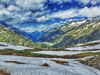 Scenic view of snow covered mountains against cloudy sky