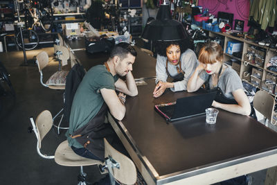 High angle view of mechanics using laptop at table in workshop