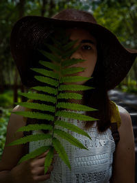 Close-up portrait of woman holding fern leaves