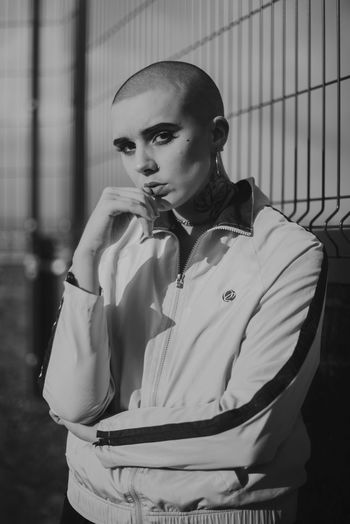 CLOSE-UP PORTRAIT OF YOUNG WOMAN STANDING AGAINST WALL