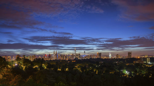 Illuminated cityscape against sky at night