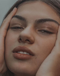 Close-up portrait of tired young woman with hand on chin